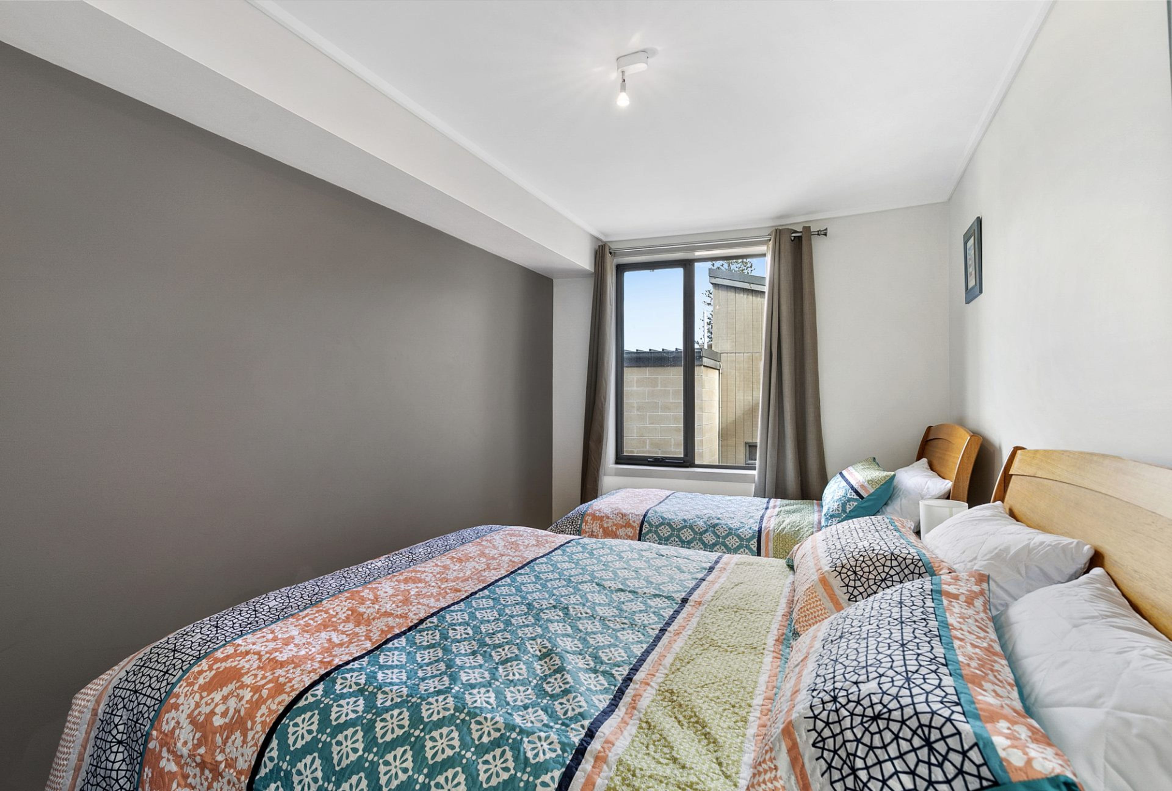 A hotel room with two beds, a large window, and a view of the outside.