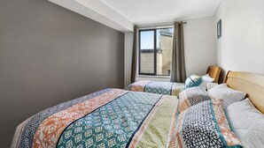 A hotel room with two beds, a large window, and a view of the outside. - Apartment 29 Pacific Apartments (Lorne)