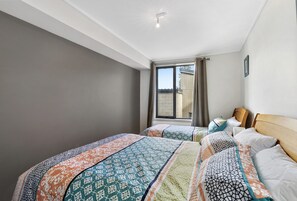 A hotel room with two beds, a large window, and a view of the outside. - Apartment 29 Pacific Apartments (Lorne)
