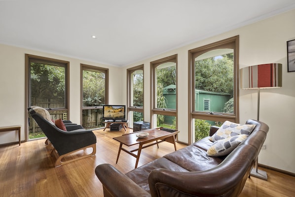 A spacious living room with a leather sofa, a coffee table, and a television on a stand.