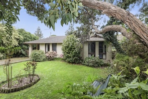 A house with a garden, a bench, and a tree.