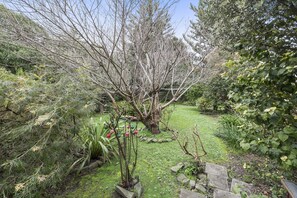 Ein Garten mit vielfältigen Pflanzen und Bäumen, einem Kiesweg und einem kleinen Teich.