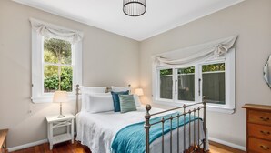 Une chambre à coucher avec un lit, des tables de chevet, une commode et des fenêtres avec des rideaux.