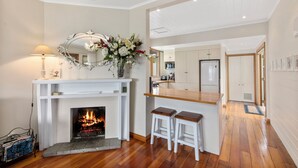 Une cuisine moderne avec des meubles blancs, un îlot central et une cheminée où le feu crépite.