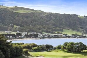 A coastal town with a golf course, residential buildings, and a hilly backdrop. - Apollo Blue 12 (Apollo Bay)