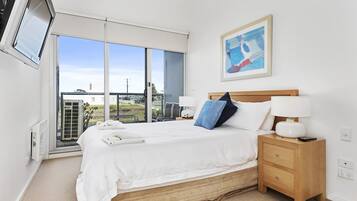 A bedroom with a bed, bedside table, lamp, and a painting on the wall.