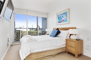 A bedroom with a bed, bedside table, lamp, and a painting on the wall.