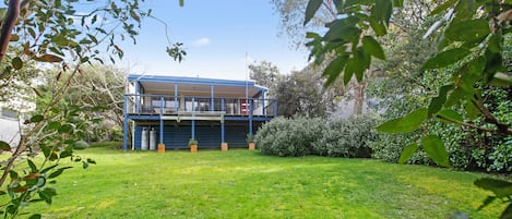 A two-story building with a balcony, surrounded by a grassy lawn and trees.