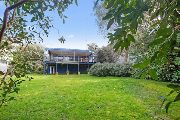 A two-story building with a balcony, surrounded by a grassy lawn and trees.