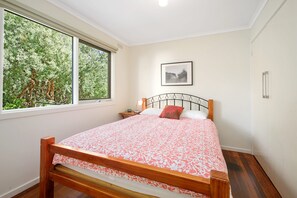 A bedroom with a bed, a window, a bedside table, and a framed picture on the wall. - Beach Fig (Skenes Creek, Apollo Bay)