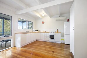 A kitchen with white cabinets, a wooden countertop, a microwave, an oven, and a refrigerator.