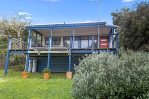 A two-story building with a balcony, a red door, and a fenced area with gas cylinders. - Beach Fig (Skenes Creek, Apollo Bay)