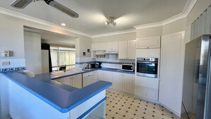 Eine moderne Küche mit blauer Arbeitsplatte, weißen Schränken, einer Mikrowelle, einem Backofen und einem Deckenventilator.