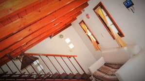 A room with a sloped ceiling, a staircase, a bed, and a window with curtains. - Cabañas San Gabriel Arcangel (Capilla del Monte)