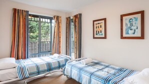 A room with two single beds, a window with curtains, and two framed pictures on the wall. - Carrageen (Lorne)