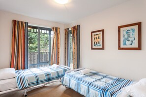 A room with two single beds, a window with curtains, and two framed pictures on the wall. - Carrageen (Lorne)