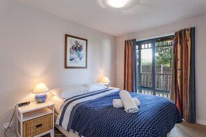 A hotel room with a bed, two bedside lamps, a wall-mounted picture, and a window with curtains. - Carrageen (Lorne)