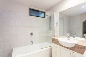 A modern bathroom with a bathtub, a shower, and a double sink. - Carrageen (Lorne)