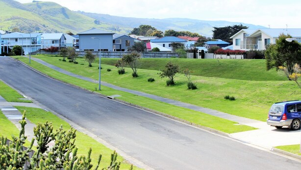 A residential street with houses, a clear sky, and a blue car parked on the side. - Beach Retreat (Apollo Bay)
