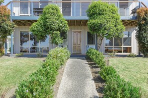 Una moderna casa a due piani con vialetto in ghiaia e filare di siepi curate.