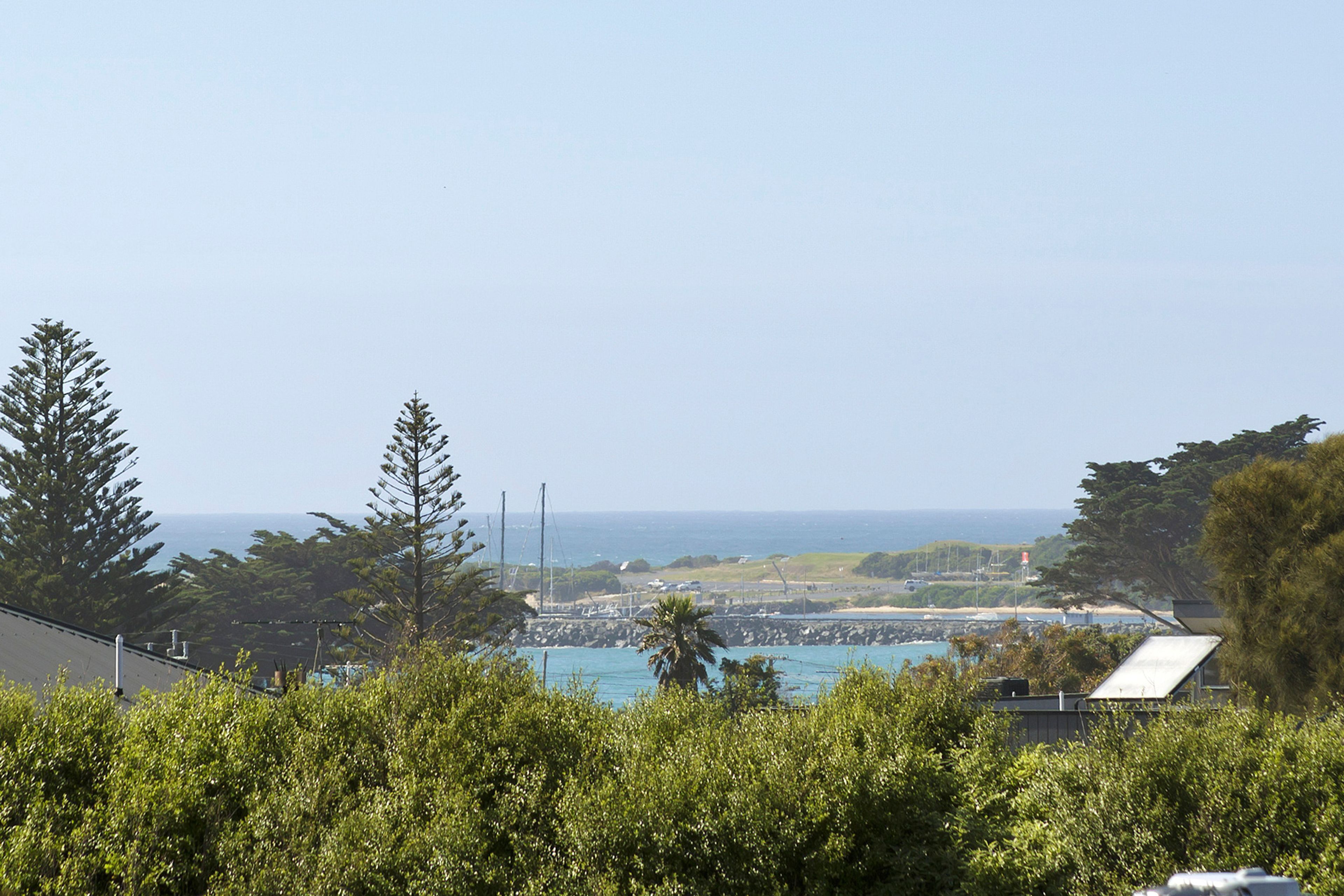 Un paisaje costero con vista al mar, vegetación y una costa distante.
