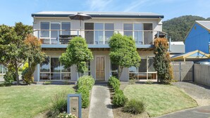 A two-story residential building with a balcony, a front door, and a small driveway. - Beach Retreat (Apollo Bay)