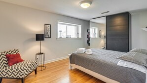 Un dormitorio moderno con una cama, una silla, una lámpara de pie y un ventanal.