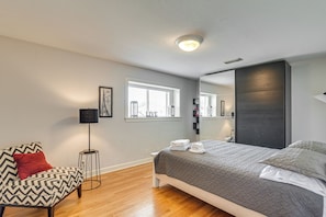Un dormitorio moderno con cama, una silla, una lámpara de pie y una ventana con persianas.