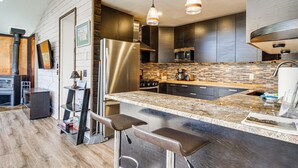 Una cocina moderna con una isla central, electrodomésticos de acero inoxidable y un salpicadero de baldosas en espiga.