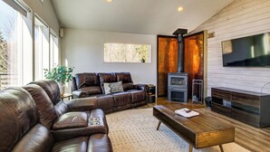 Una sala moderna con un sofá de cuero, una mesa de centro de madera, una chimenea y un televisor grande montado en la pared.
