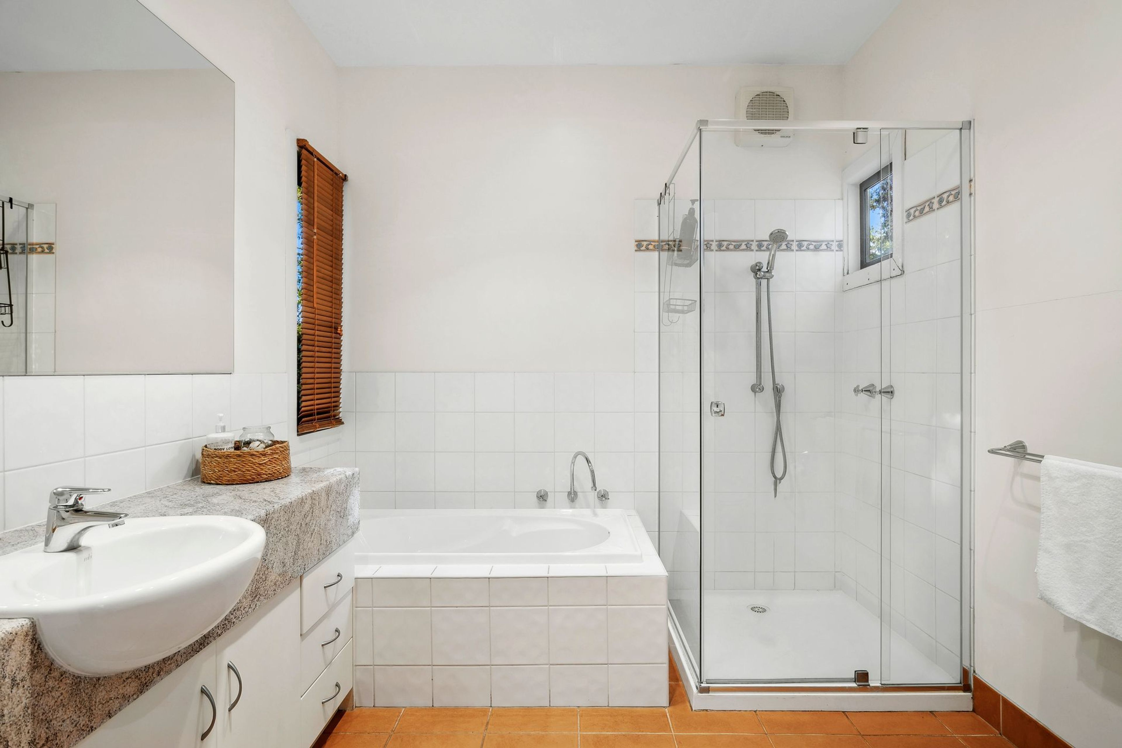 Een badkamer met een bad, douche, wastafel en spiegel.