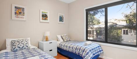 Une chambre avec deux lits, une table de chevet et une fenêtre donnant sur l’extérieur.