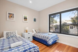 Une chambre avec deux lits, une table de chevet et une fenêtre donnant sur l’extérieur.