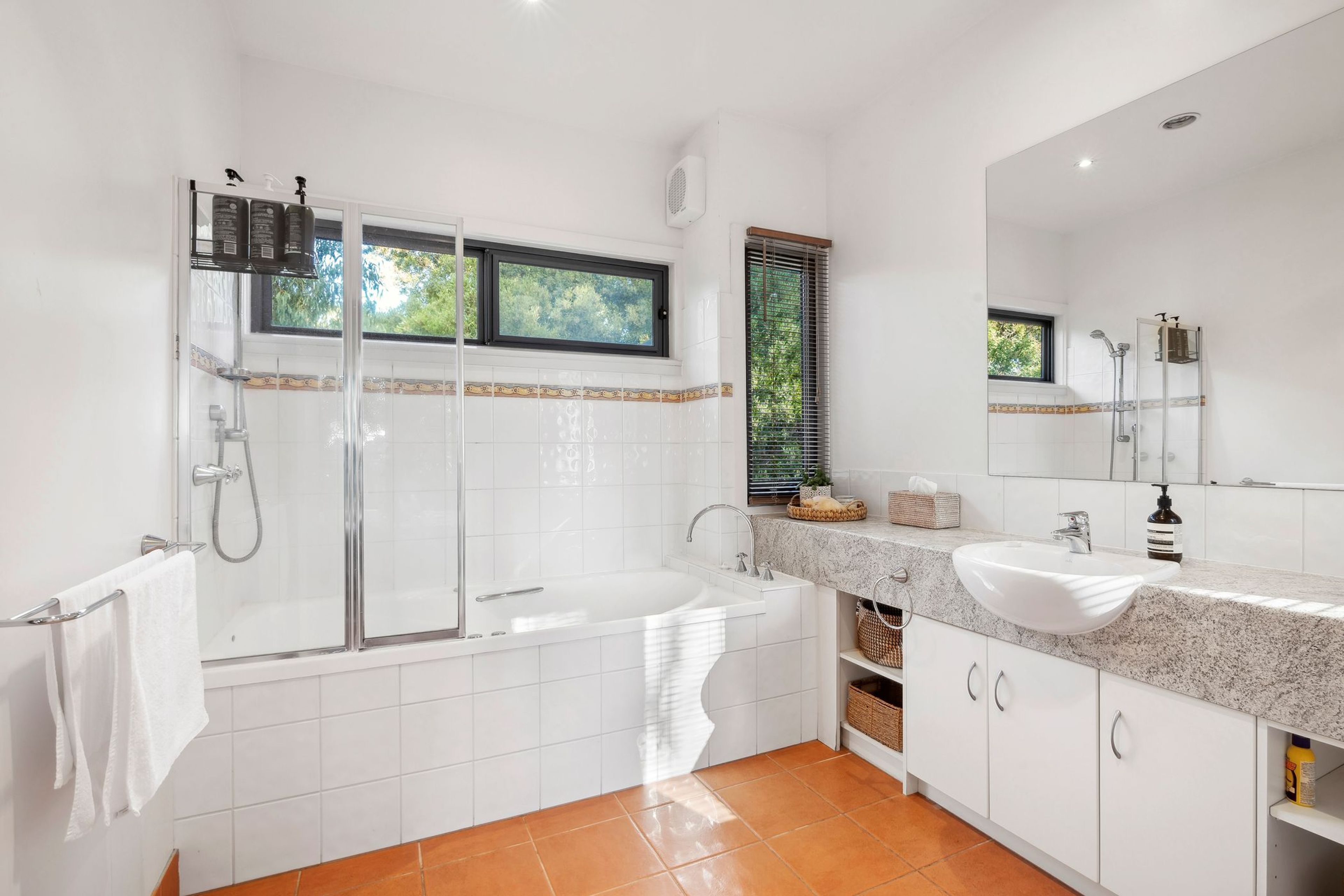 A modern bathroom with a glass-enclosed shower, a freestanding bathtub, and a vanity with a large mirror.