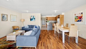 A modern apartment with a living room, dining area, and kitchen. - Apartment 23 Pacific Apartments (Lorne)
