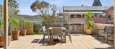 An outdoor patio with a table and chairs, surrounded by potted plants and overlooking a scenic view.