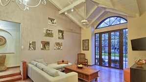 A spacious living room with a large sectional sofa, a wooden coffee table, and a large window with a view of the outdoors. - Villa Doña Iñes - Privacy! Gorgeous home, guest house & pool, free wifi! (Tamarindo)