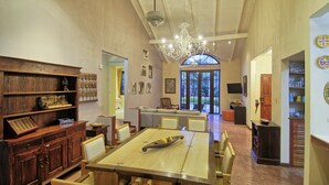 A spacious living area with a high ceiling, a chandelier, and a dining table with chairs. There is a fireplace, a sofa, and a television in the background. - Villa Doña Iñes - Privacy! Gorgeous home, guest house & pool, free wifi! (Tamarindo)