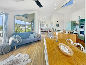 A modern living room with a sofa, dining table, and kitchen area.