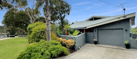 A modern two-story house with a garage, surrounded by a well-maintained lawn and various shrubs.