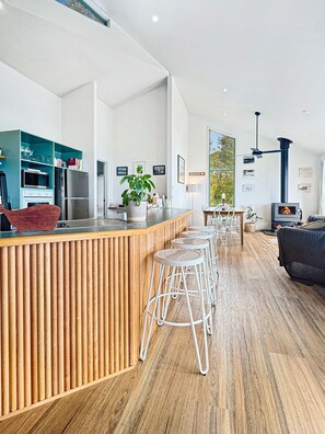 A modern kitchen with a wooden island, bar stools, and a built-in stove.