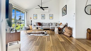 A modern living room with a sofa, coffee table, and a view of the outdoors. - SeaEsta - Modern Beachside Escape North Lorne (Lorne)