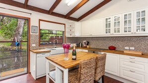 A modern kitchen with white cabinetry, a wooden dining table, and a view of the outdoors.