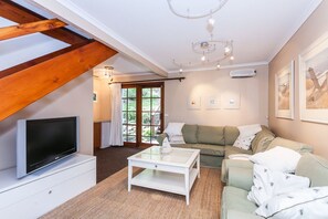 Un salon avec une télévision, un canapé, une table basse et un escalier.