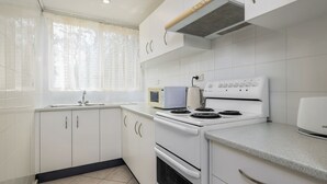 Una cocina con armarios blancos, estufa, microondas y lavaplatos.