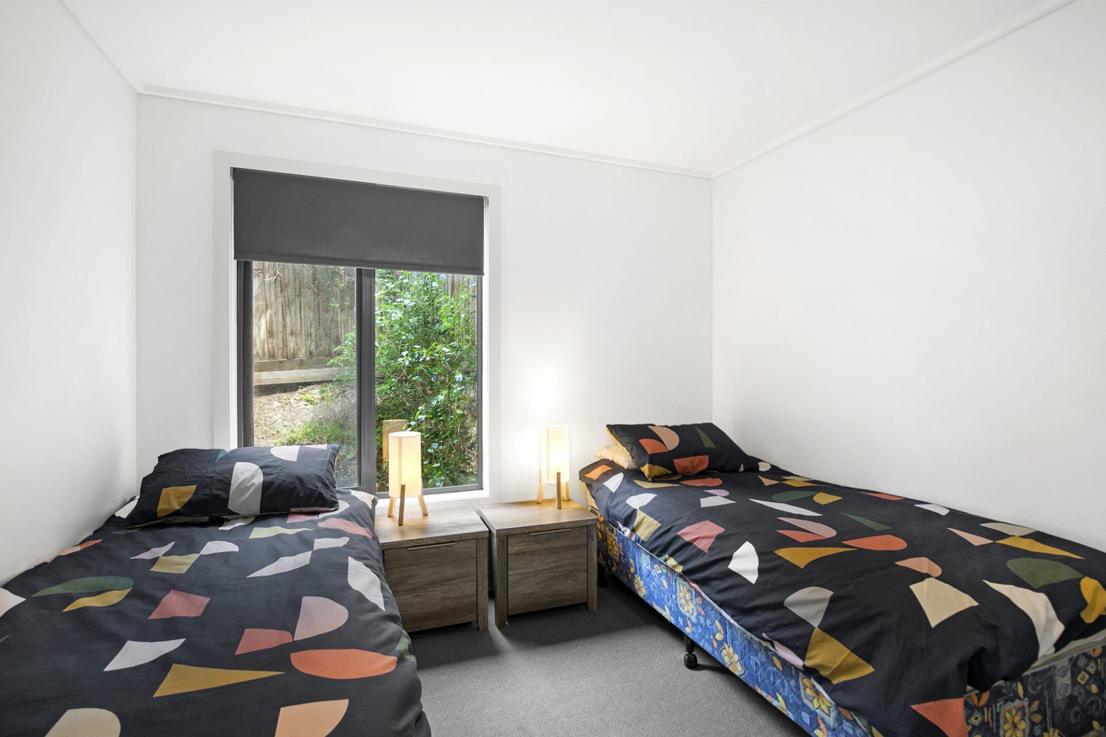 Una camera da letto con due letti, una finestra e un comodino con una lampada.
