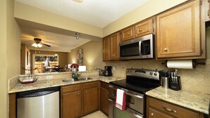 Cucina con mobili in legno, elettrodomestici in acciaio inossidabile, lavastoviglie e piano di lavoro con lavello.
