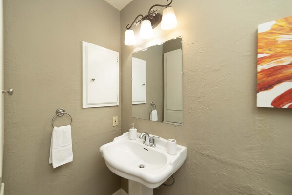 A bathroom with a white sink, a mirror, and a towel rack.