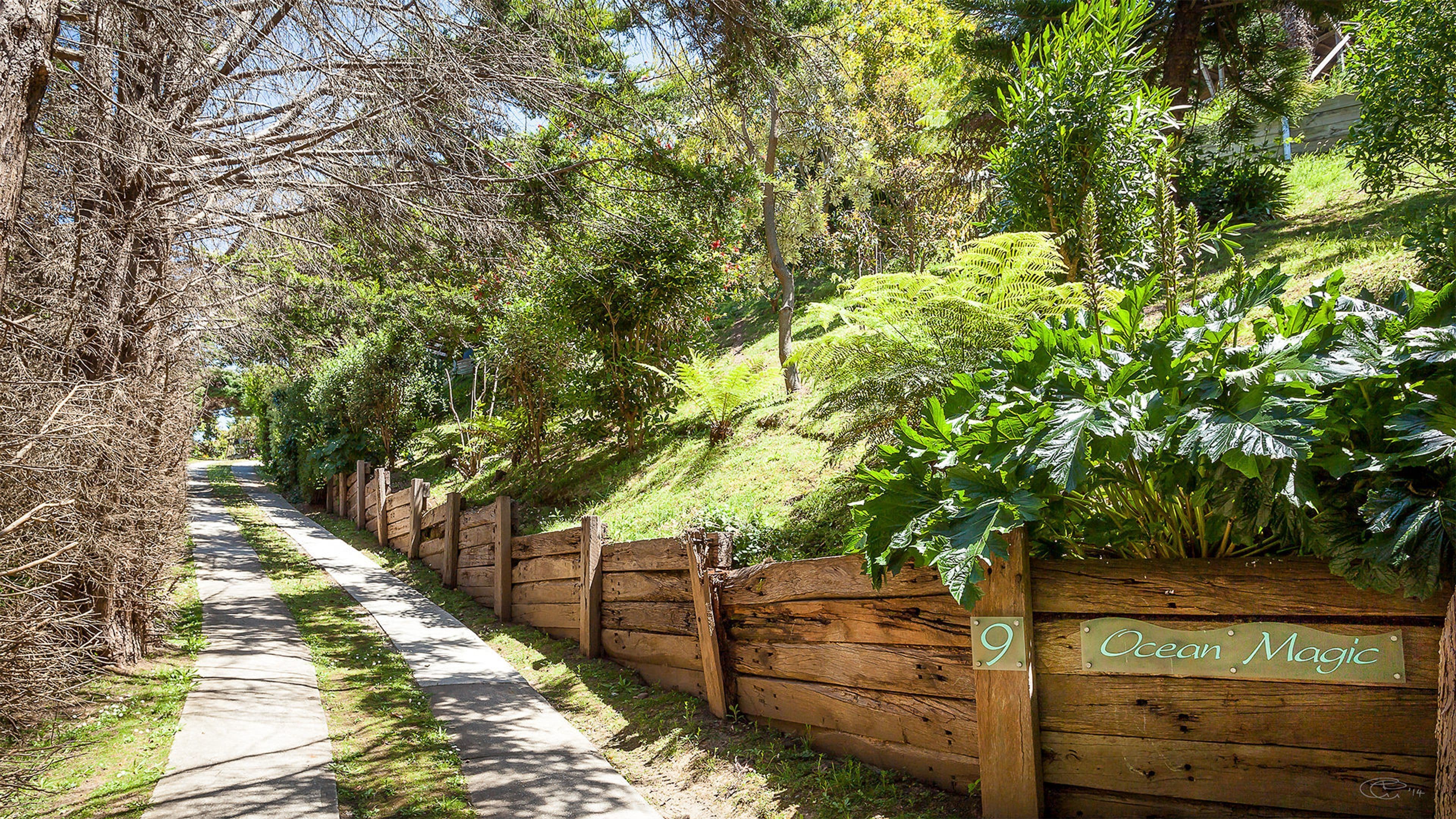 Un sendero bordeado por una valla de madera con un letrero que dice 'Ocean Magic'.