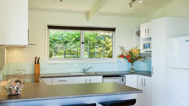 Una cucina moderna con una finestra, elettrodomestici in acciaio inossidabile e un vaso con fiori.
